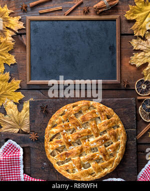 empty black chalk board and baked whole fruit cake on brown wooden background, apple pie recipe Stock Photo