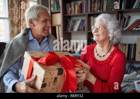 Senior Couple Exchanging Christmas Gifts at Home Stock Photo