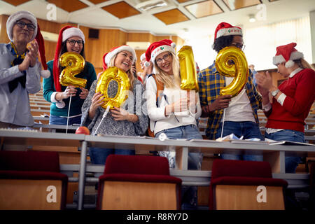 Group of smiling colleagues in Santa hat having fun at new year celebration on university Stock Photo