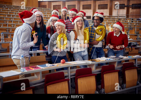 Group of colleagues in Santa hat having fun at new year celebration on university Stock Photo