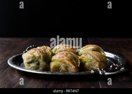 Turkish Midye Baklava ( Mussel Shape Baklawa ) with green pistachio Powder and Butter Cream in Silver Tray. Dessert with Pistachio Stock Photo