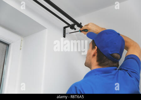handyman services - worker installing window curtain rod on the wall Stock Photo