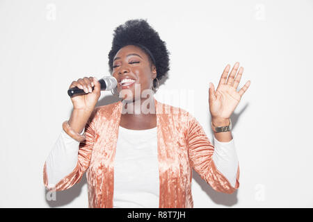 Woman singing with microphone Stock Photo