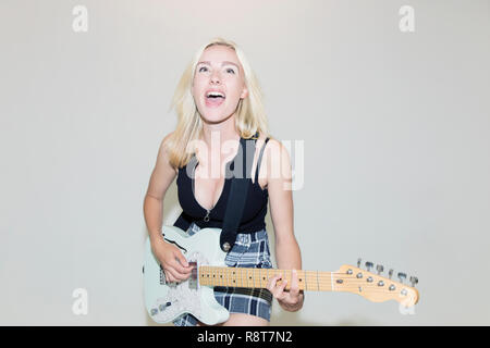 Exuberant young woman playing electric guitar Stock Photo