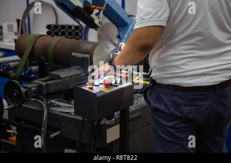 Worker operate band saw machine cutting metal workpiece Stock Photo