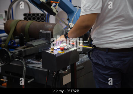 Worker operate band saw machine cutting metal workpiece Stock Photo