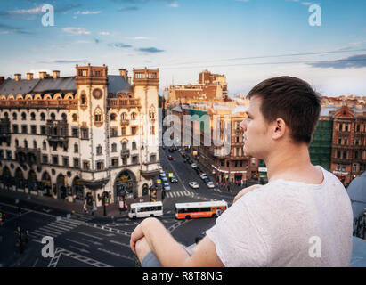 Young man is sitting on a roof and looking Leo Tolstoy square in Saint Petersburg in evening, Russia Stock Photo