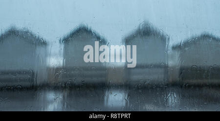 Lyme Regis, Dorset, UK. 18th December 2018.  UK Weather: A Wet and windy day at Lyme Regis.  Wet beach huts on Monmouth Beach as heavy downpours hit the coast at Lyme Regis.  A Yellow Warning of rain has been issued along the South West Coast. Credit: PQ Images/Alamy Live News Stock Photo