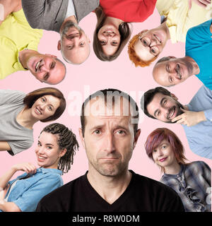 Middle aged stressed man looking at camera. People are smiling and laughing on background. Stock Photo