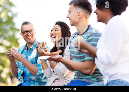 happy friends eating sandwiches and pizza outdoors Stock Photo