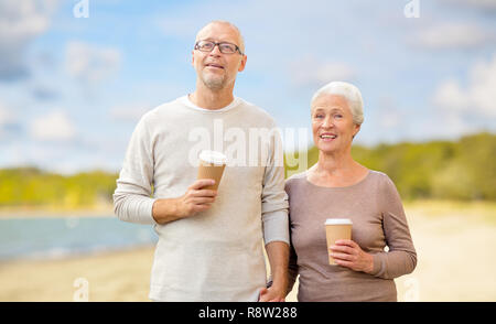 senior couple with takeaway coffee on beach Stock Photo
