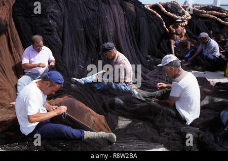 Fishermen repairing fishing nets on quayside, Olhao, Algarve, Portugal, Europe Stock Photo