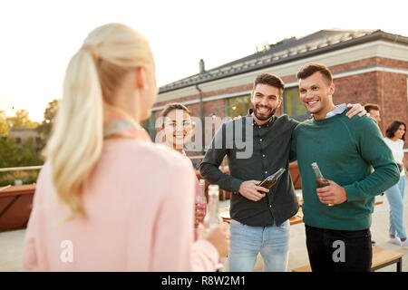 happy friends with drinks hugging at rooftop party Stock Photo