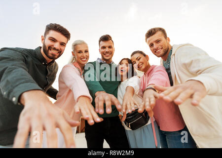 happy friends reaching hands to you Stock Photo