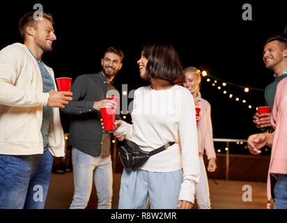 friends with drinks dancing at rooftop party Stock Photo