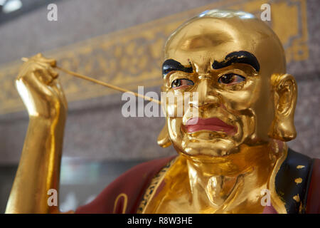 Detail of Gilt Lohan Arhat cleaning his ears with stick inside Kuang Im Chapel, near River Kwai, Kanchanaburi, Thailand. Stock Photo