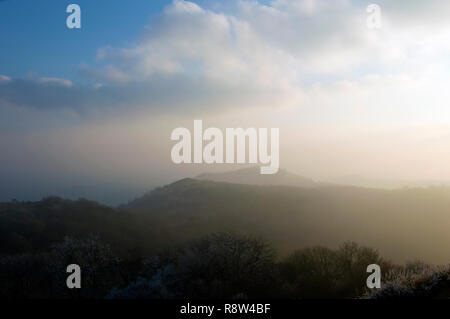 Looking across the ridge and woodlands of the Malvern Hills on a cold, frosty, misty afternoon. Worcestershire, UK. Stock Photo