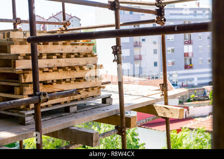 Above view on piled stocked wooden industrial pallets at building site, residential edifice under construction. Stock Photo