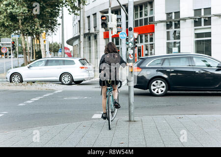 The girl on the bike stopped at a red light and waiting for when to go. Riding a bike or a healthy lifestyle. Stock Photo