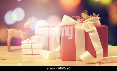 Modern gold, copper and white wrapped gift in front of bokeh lights of Christmas tree, with applied filters. Stock Photo