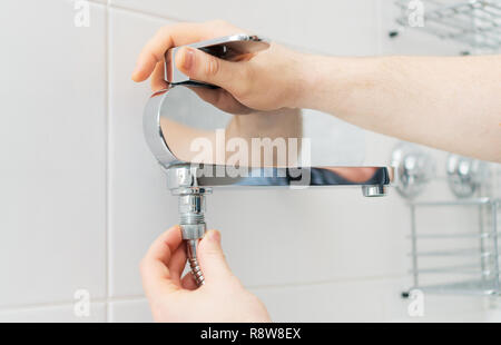 Plumber hands fixing shower mixer on modern water tap. Stock Photo