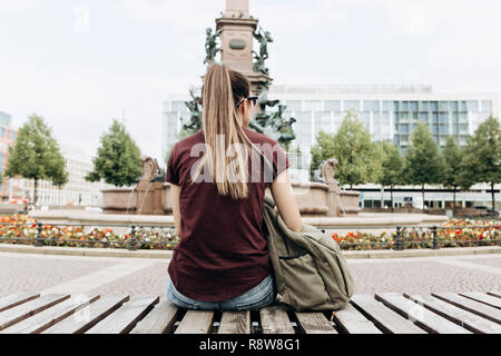 A tourist sits on a bench in a city park in Leipzig in Germany and rests. Stock Photo