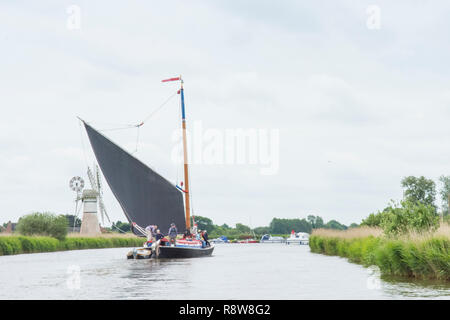 Wherry, traditional sailing boat on Norfolk Broads, River Thurne, in front of Thurne Dyke Drainage Mill. June. Stock Photo
