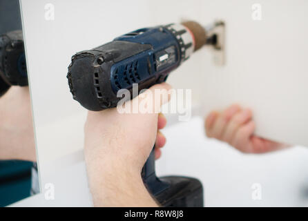 Handyman installing cabinet door in bathroom. Stock Photo