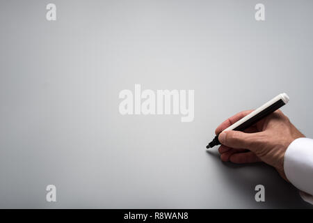 Male hand writing on grey background with black marker. Plenty of copy space. Stock Photo