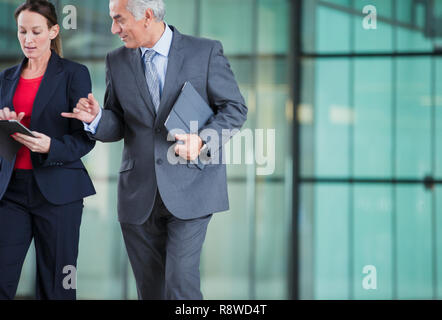 Business people with digital tablet walking and talking Stock Photo