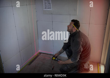 Construction worker using laser measuring tool Stock Photo