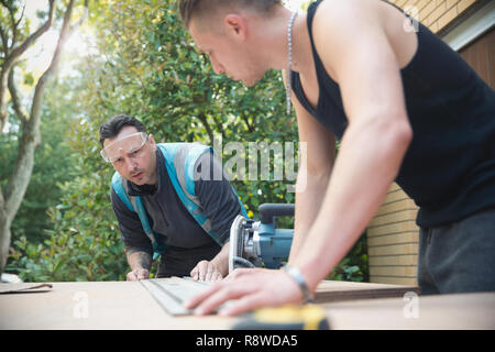 Construction workers measuring wood in driveway Stock Photo
