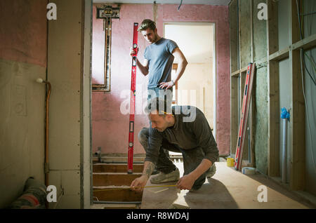 Construction workers using tape measure and level tool in house Stock Photo