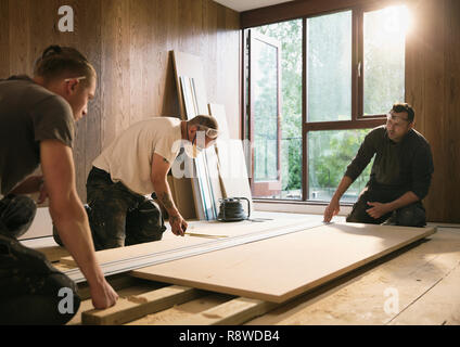 Construction workers measuring wood board Stock Photo