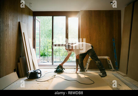 Construction worker using electric saw to cut wood in house Stock Photo