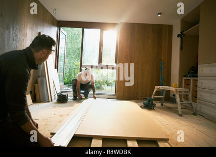 Construction workers measuring wood board in house Stock Photo