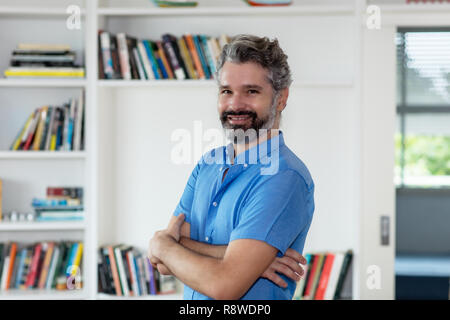 Older man with grey hair and arms crossed indoor at home Stock Photo