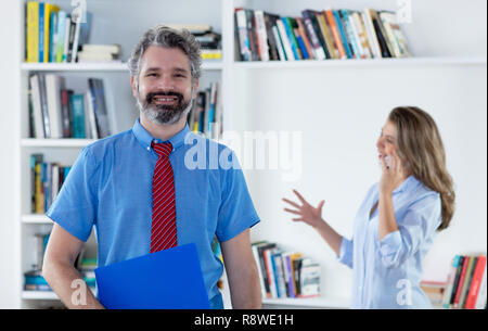 Laughing businessman with grey hair and blond secretary at office Stock Photo