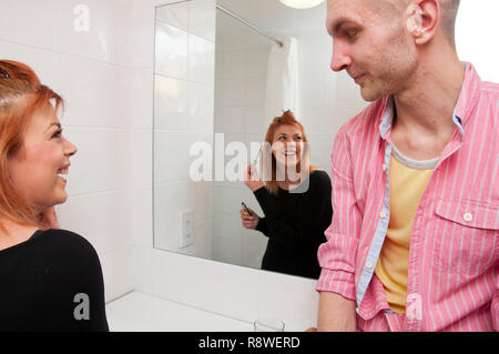 Young couple talking in hotel bathroom while woman is getting ready. Stock Photo