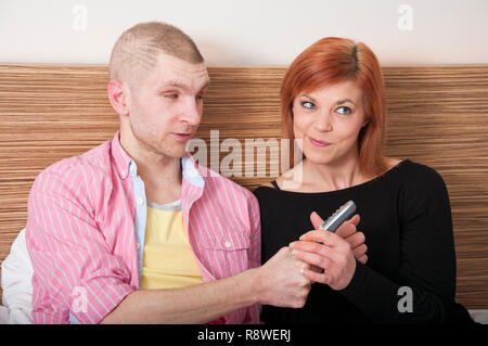 Young couple arguing fighting over TV remote control. Stock Photo