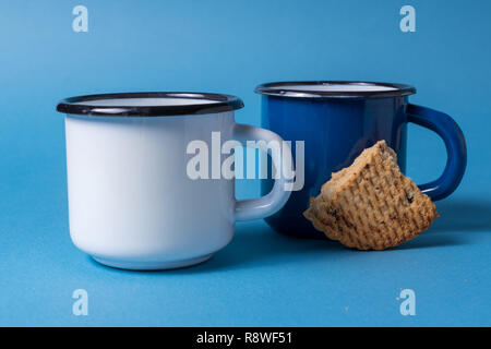 Front view White and blue enameled mugs on blue background. Stock Photo