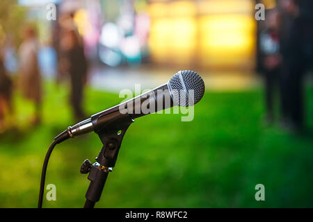 Close up classic microphone on Abstract blurred bright green background of conference hall or event. Public speaking concept. Selective focus. copy sp Stock Photo