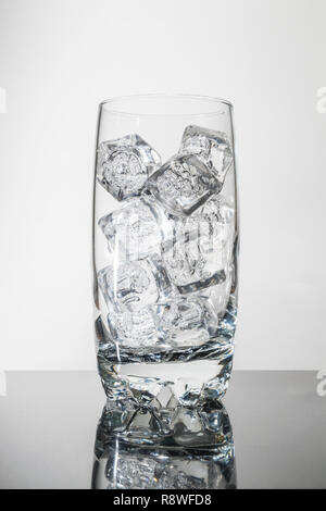 ice cubes in glass tumbler on shiny tabletop Stock Photo