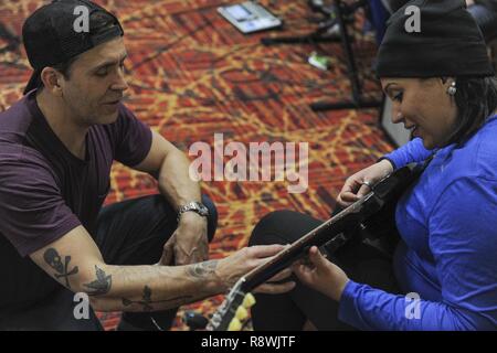 Former Korn guitarist and Rock to Recovery founder Wes Geer gives pointers to an Air Force Wounded Warrior Trials participant during a Rock to Recovery practice session in Las Vegas, March 1, 2015. Rock to Recovery brings together people suffering from similar ailments and each participant shares their personal story before choosing from a variety of instruments to play as part of a band. Stock Photo