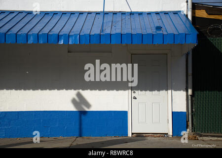 Blue and White painted brick building with blue aluminium awning and white door Stock Photo