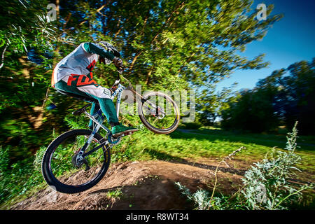 Moscow, Russia - August 31, 2017: Jump and fly on a mountain bike. Rider in action at mountain bike sport. Biker riding in forest. Cool athlete cyclis Stock Photo