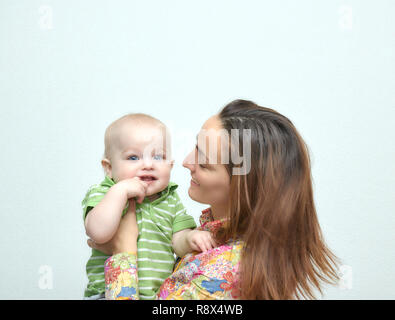brunette young mom, girl holding a little baby boy in her arms frolicking. family atmosphere with smiles. happy family smiles. Stock Photo