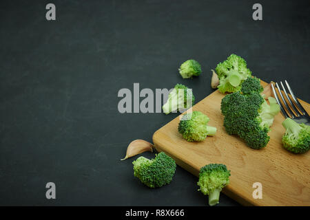 placer green broccoli segments from a small bucket. Healthy eating pattern on dark background. Copy space Top view. Vegetarian food. Stock Photo