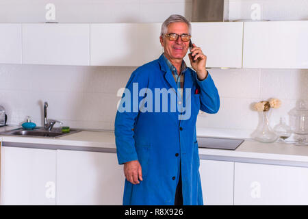 Workman standing in the kitchen, smiling and talking on cellphone Stock Photo