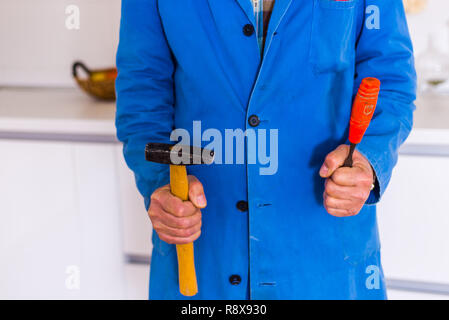 An old age handyman in overall is standing in the kitchen with his tools Stock Photo